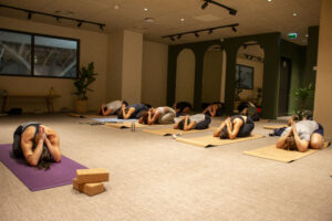 Cours de yoga collectif. Les élèves sont dans la posture de Balasana.
