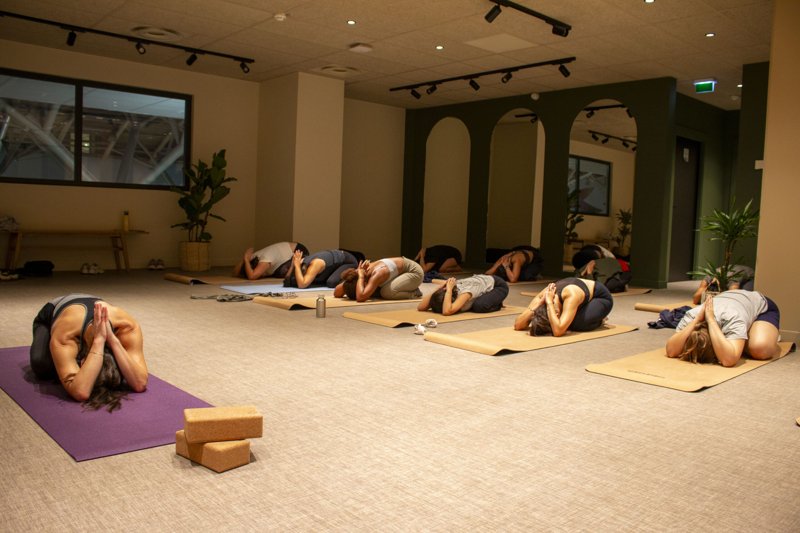ByBidâla - Cours Collectifs Cours de yoga collectif. Les élèves sont dans la posture de Balasana.